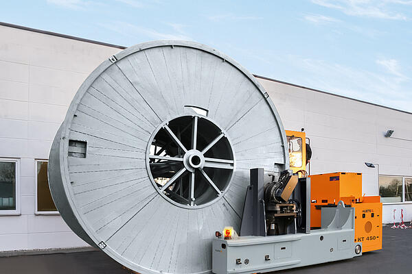 A drum transporter straddling a cable drum.